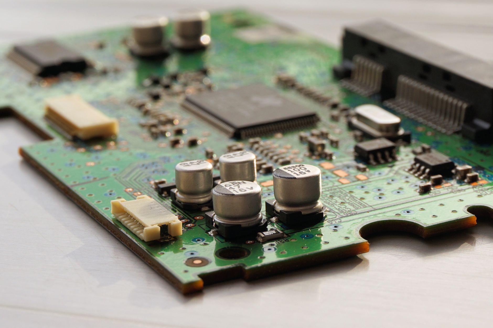 Macro photograph of a green printed circuit board with capacitors and microchips